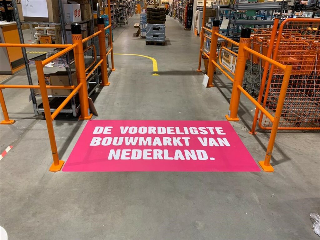 Roze vloersticker met opschrift 'de voordeligste bouwmarkt van Nederland'