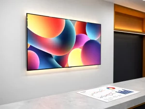 Digitaal signagescherm op winkelwand met levendige productvisuals naast een analytics-rapport op een toonbankblad.