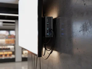 Narrowcasting pc gemonteerd achter een commercieel beeldscherm in een moderne retailomgeving met strak kabelmanagement.