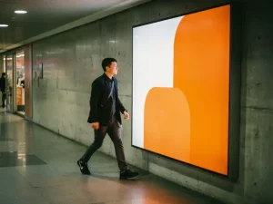 Voorbijganger die snel langs levendige oranje en witte winkelbordsignage loopt in moderne retailgang met betonnen muren.